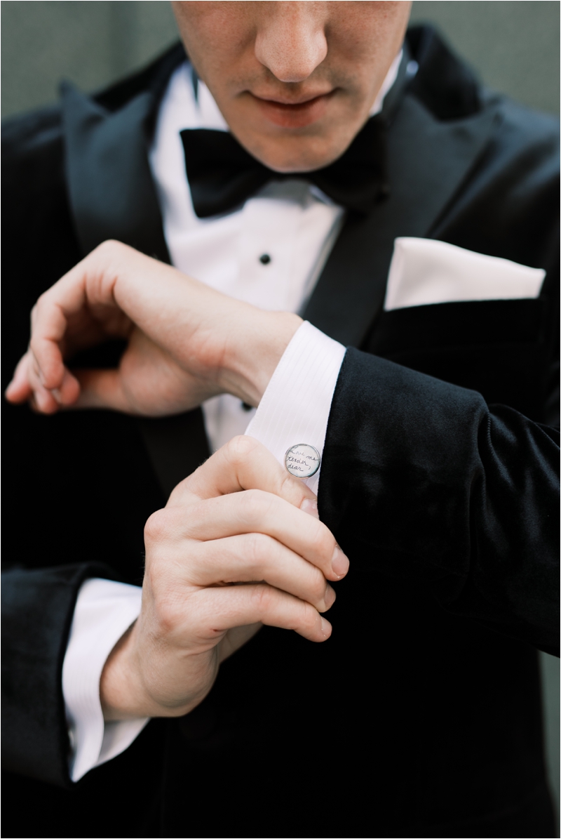 groom adjusts cufflinks for classic tux