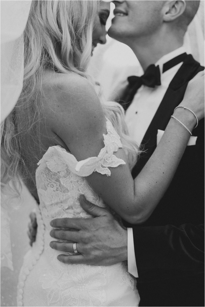 black and white portrait of groom kissing bride's forehead