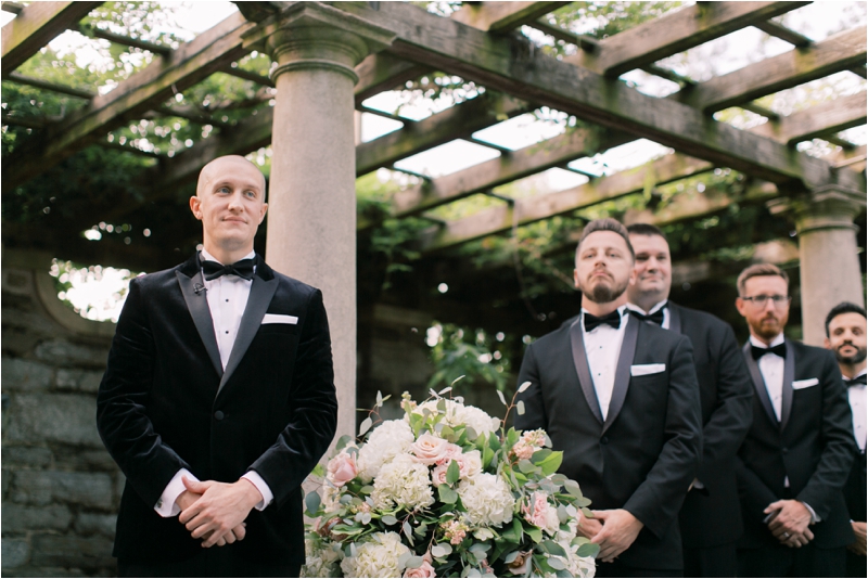 groom watches bride walk down the aisle in classic tux
