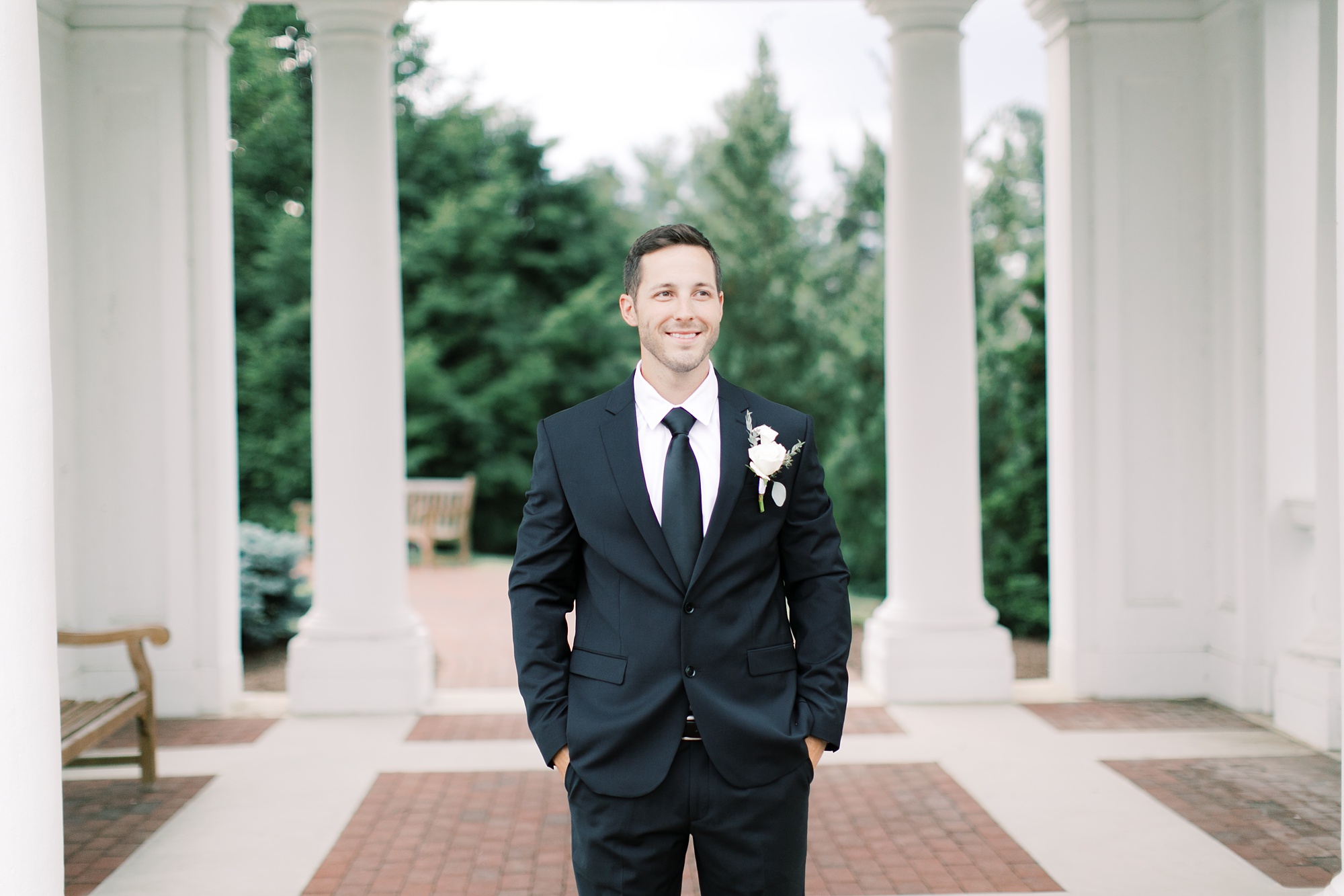 groom in black suit with white boutonniere poses during Hotel Hershey anniversary session