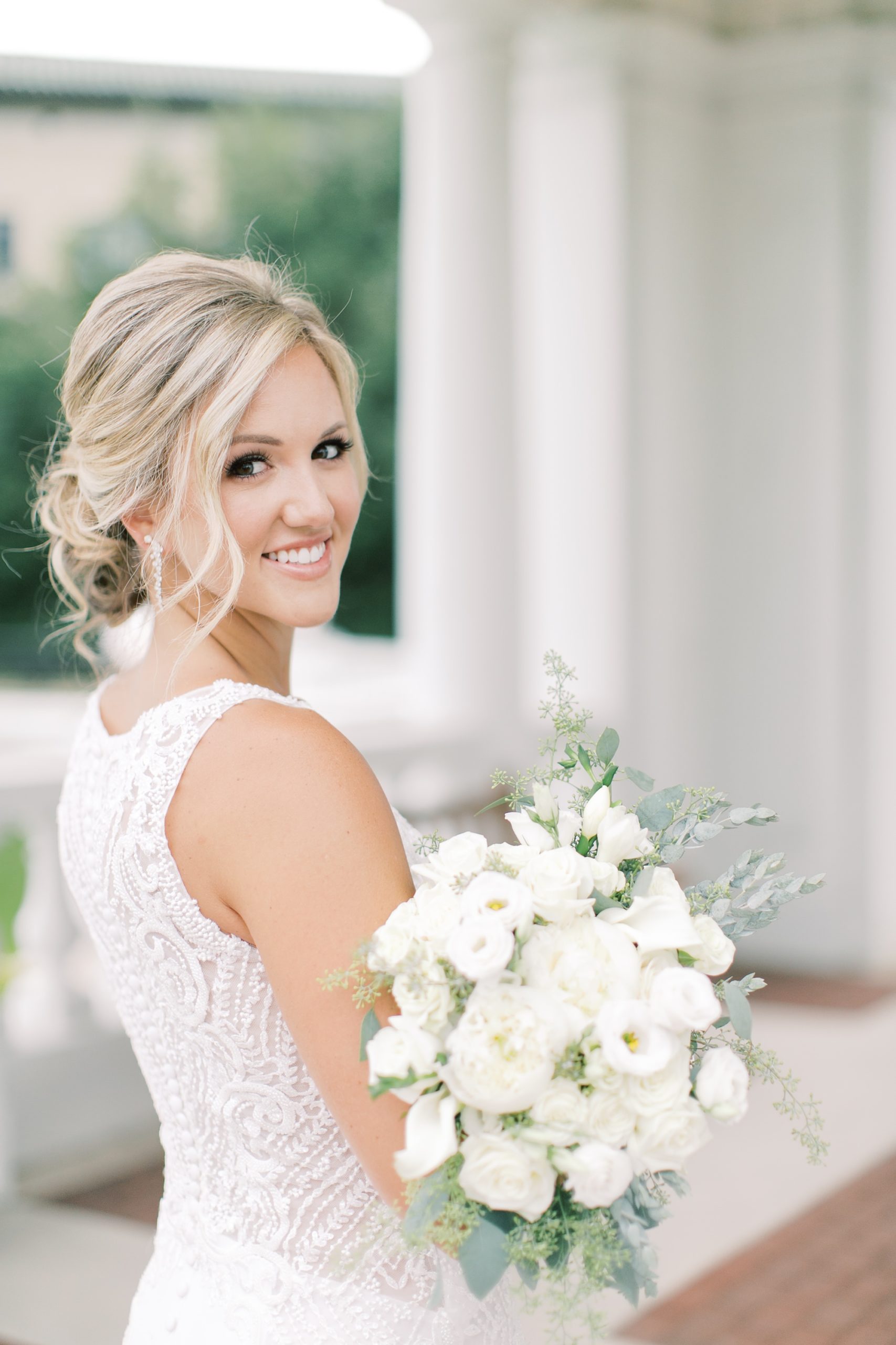 wife holds bouquet of white flowers and looks over shoulder during anniversary photos