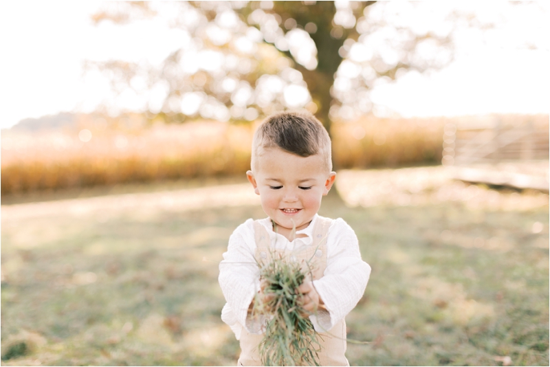 toddler plays with grass during family photos in PA