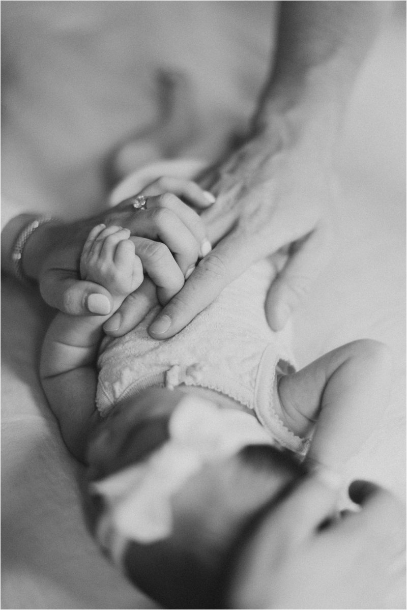 dad and mom lay hands on newborn baby girl 