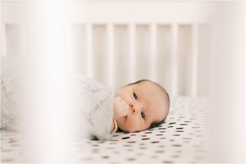 baby lays in crib during lifestyle photos at home