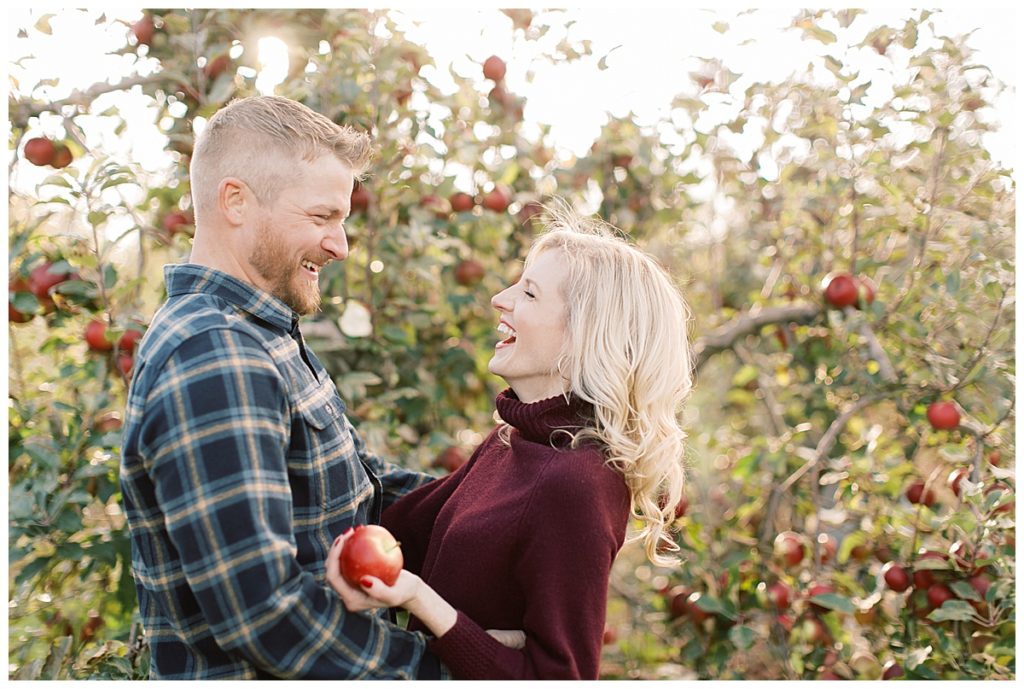 couple laughing and sharing a candid moment. Apple Orchard photography with couple laughing. 